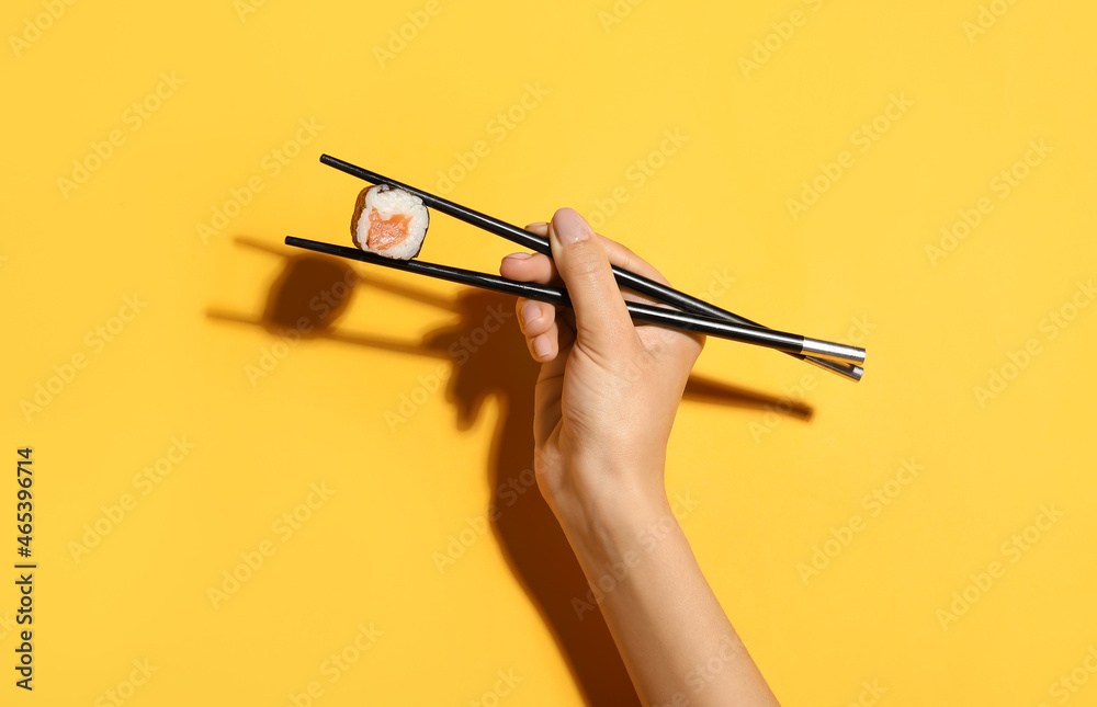 用筷子夹三文鱼寿司卷的女人