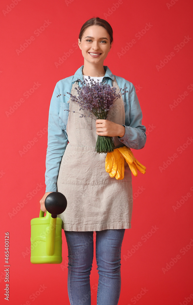 Female gardener with lavender and watering can on color background