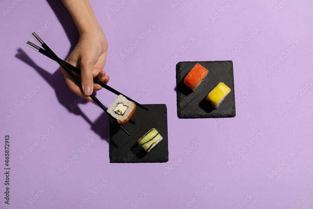 用筷子在彩色背景上拿寿司卷的女人