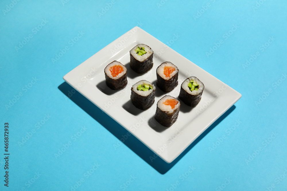 Plate with different delicious maki sushi on color background