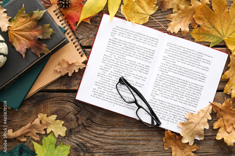 用打开的书、眼镜和木制背景上的秋叶创作