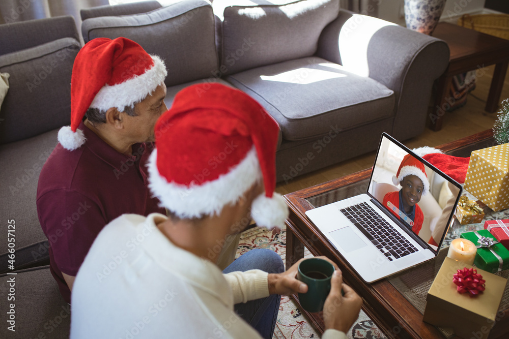 Biracial father and adult son making laptop christmas video call with smiling african american boy