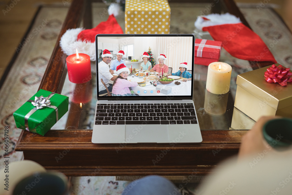 笔记本电脑圣诞视频通话屏幕上戴着圣诞老人帽微笑的多代高加索家庭