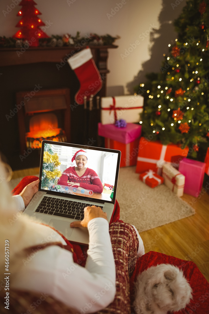 圣诞老人与戴着圣诞帽的快乐非洲裔美国妇女进行圣诞笔记本电脑视频通话