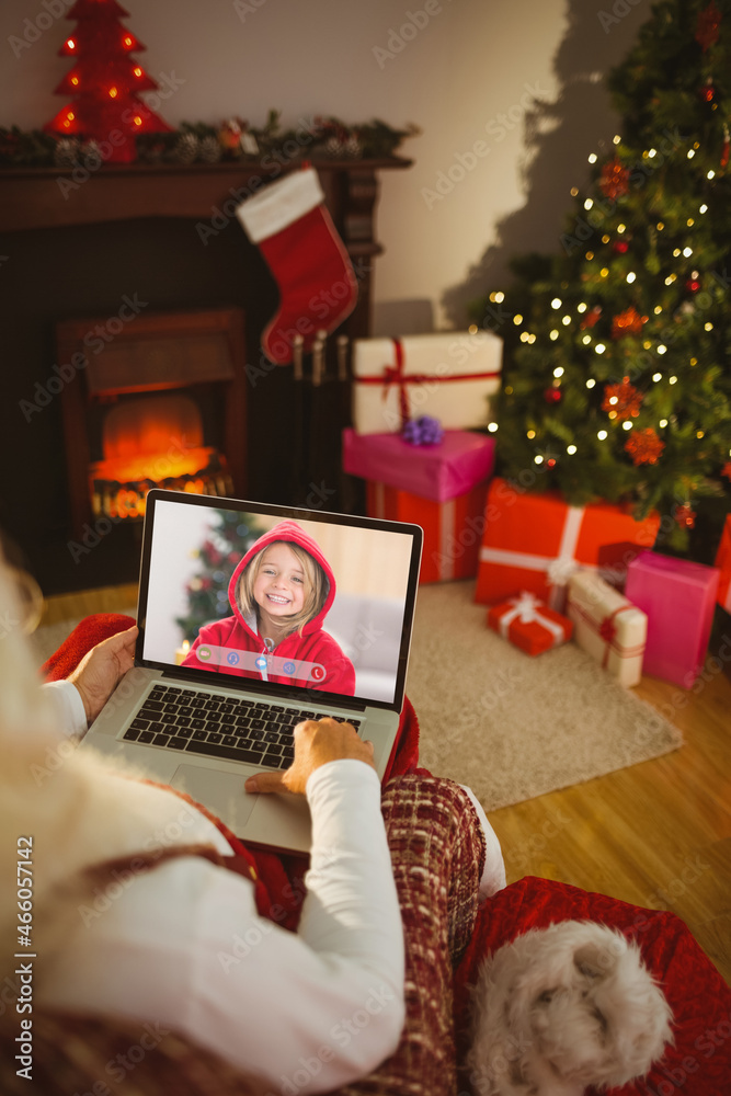 圣诞老人与快乐微笑的高加索女孩进行圣诞笔记本电脑视频通话