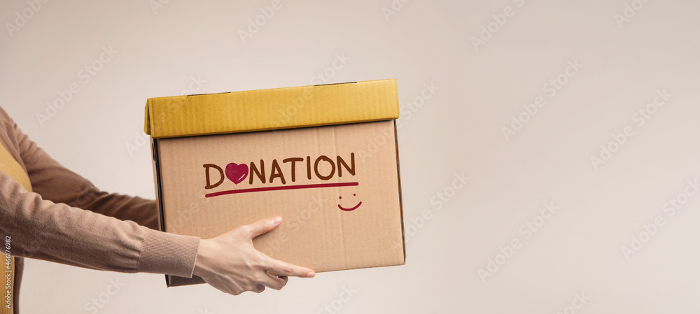 捐赠理念。带着捐赠标签、微笑和爱心的捐赠物品盒的女性。Standi