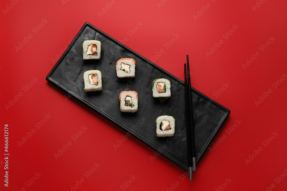 托盘上有美味的寿司卷和筷子，颜色背景