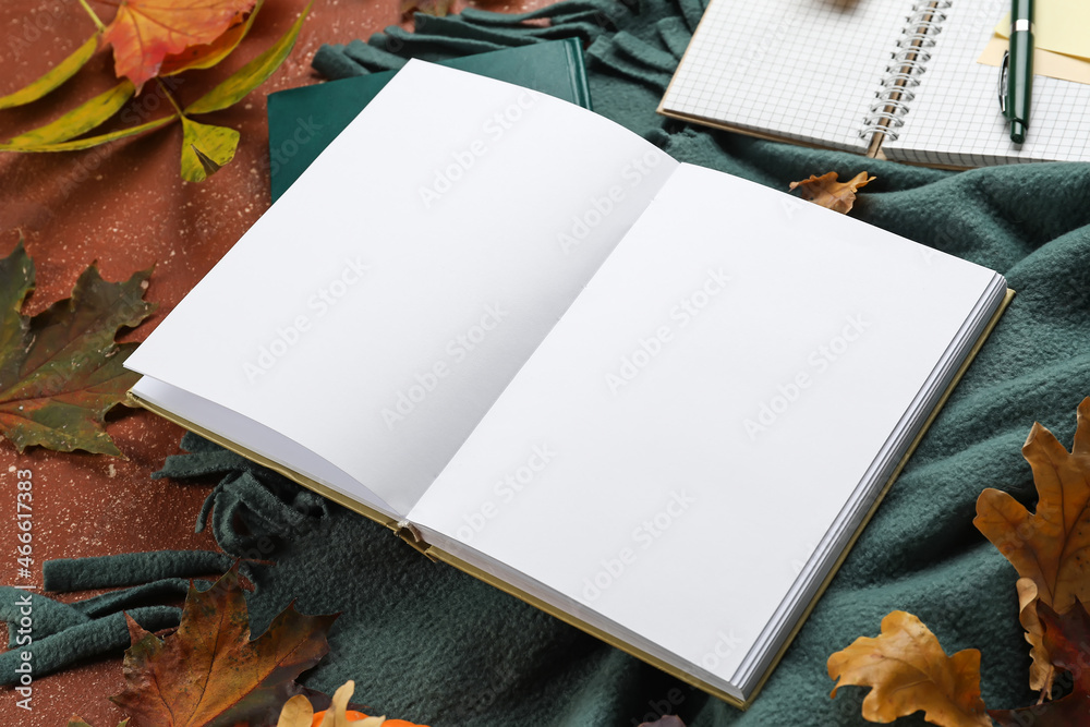 空白的打开的书和彩色背景上的秋叶，特写