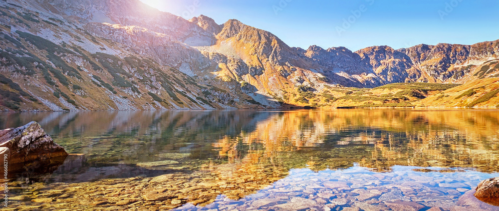 秋天的塔特拉山脉。山谷中群山环绕的蓝色湖泊大池塘中的水晶水