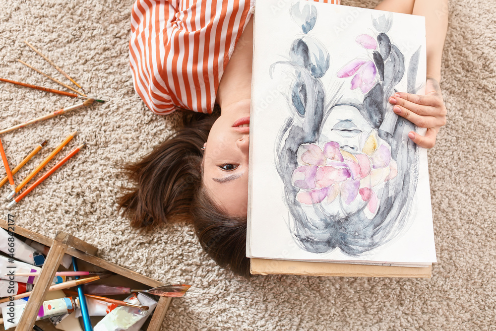 躺在家里地毯上的年轻女艺术家，俯视图