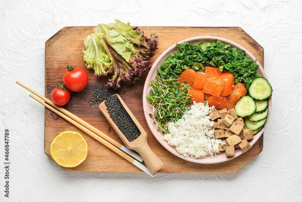 Plate with tasty rice, salmon, tofu cheese and vegetables on light background