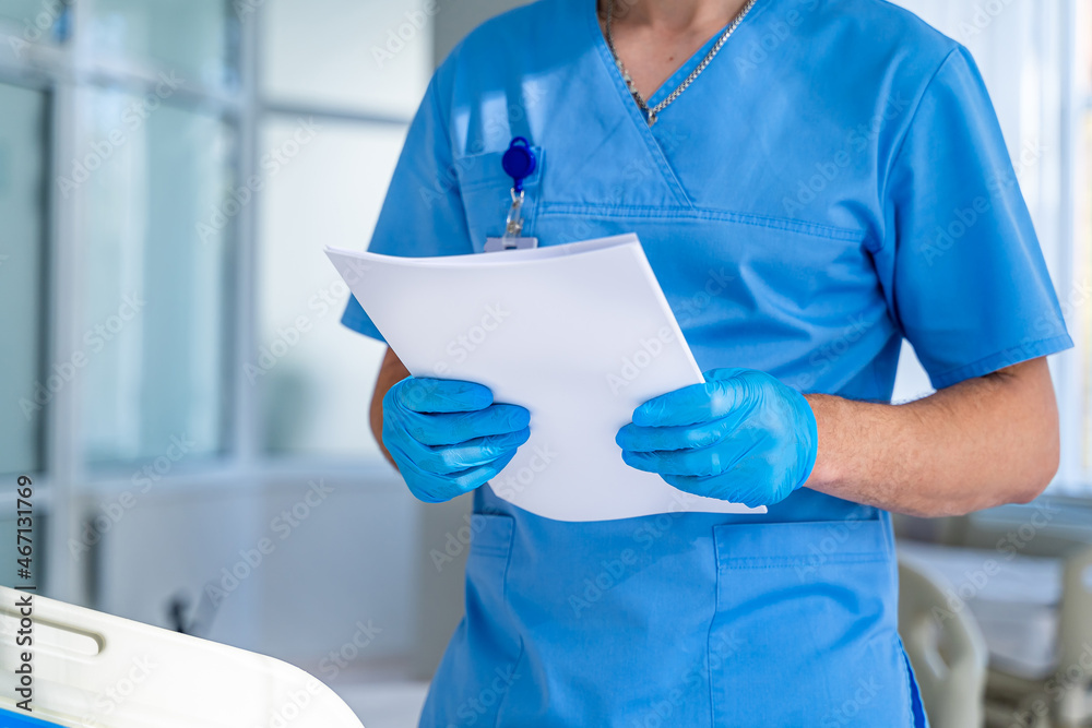 男医生穿着磨砂膏从检查表文件中读取患者信息，选择性聚焦