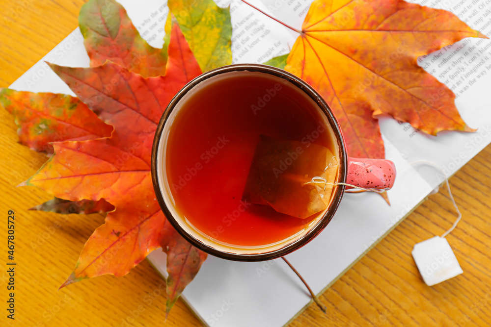 一杯热茶、书籍和木背景秋叶，特写