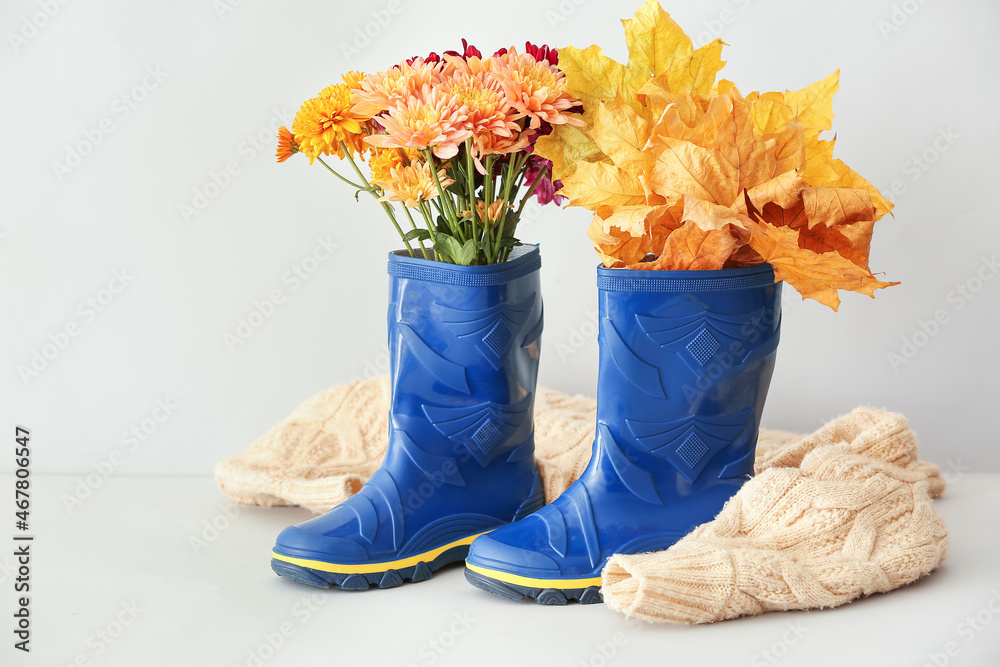 菊花、秋叶和白底毛衣的橡胶靴