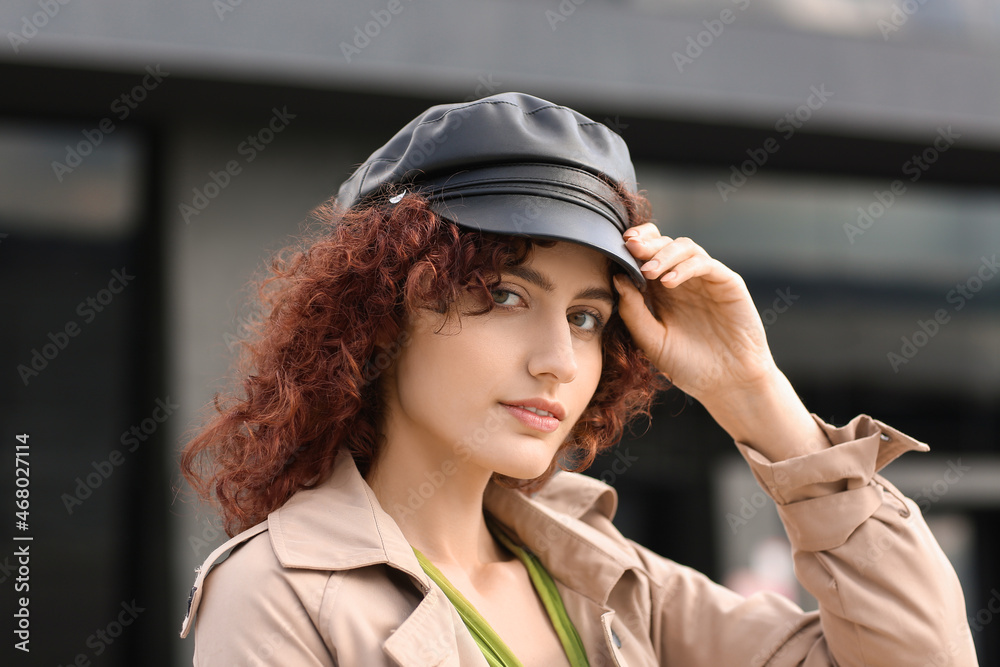 Portrait of young woman touching her leather cap outdoors, closeup