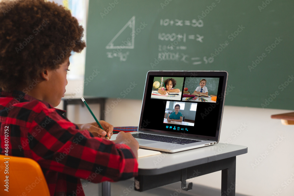 非裔美国男孩使用笔记本电脑进行视频通话，屏幕上有不同的小学生
