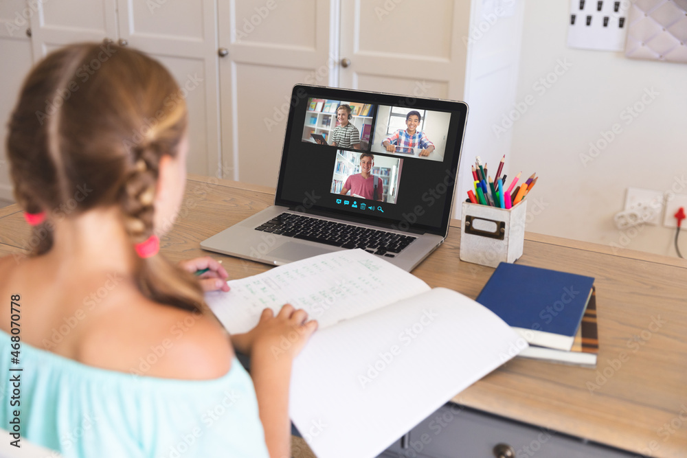 高加索女孩使用笔记本电脑进行视频通话，屏幕上有微笑的不同高中生