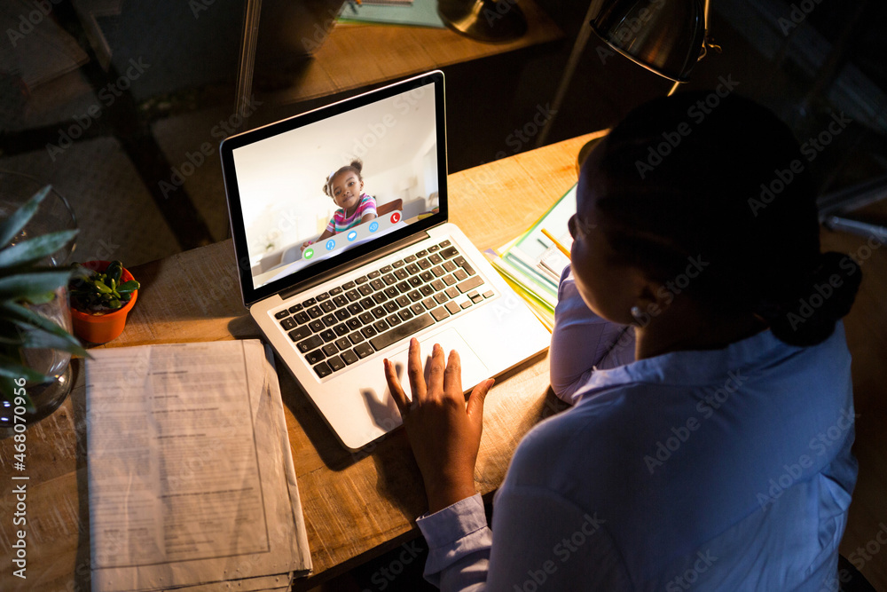 非裔美国妇女使用笔记本电脑进行视频通话，屏幕上有小学生