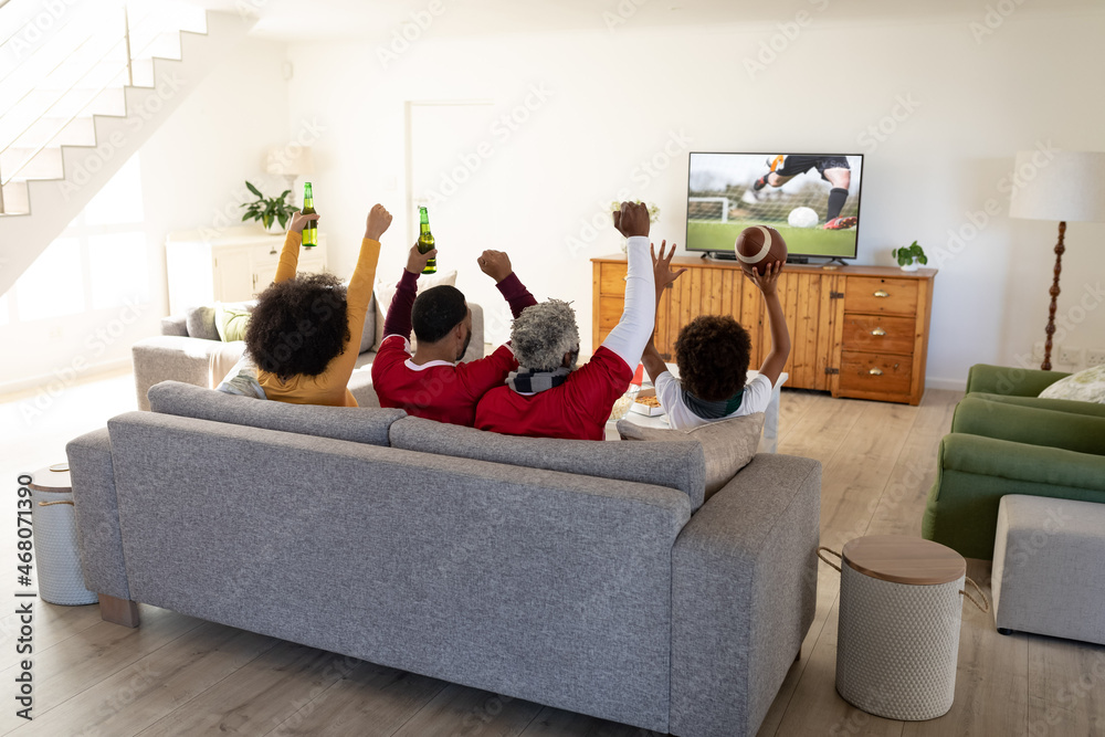 一家人坐在家里一起看电视上的足球比赛的背影