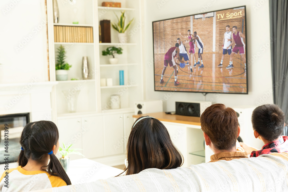 一家人坐在家里一起看电视上的篮球比赛的背影