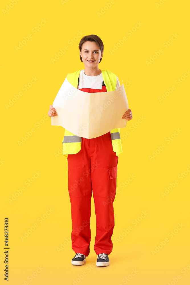 Female construction worker with house plan on yellow background