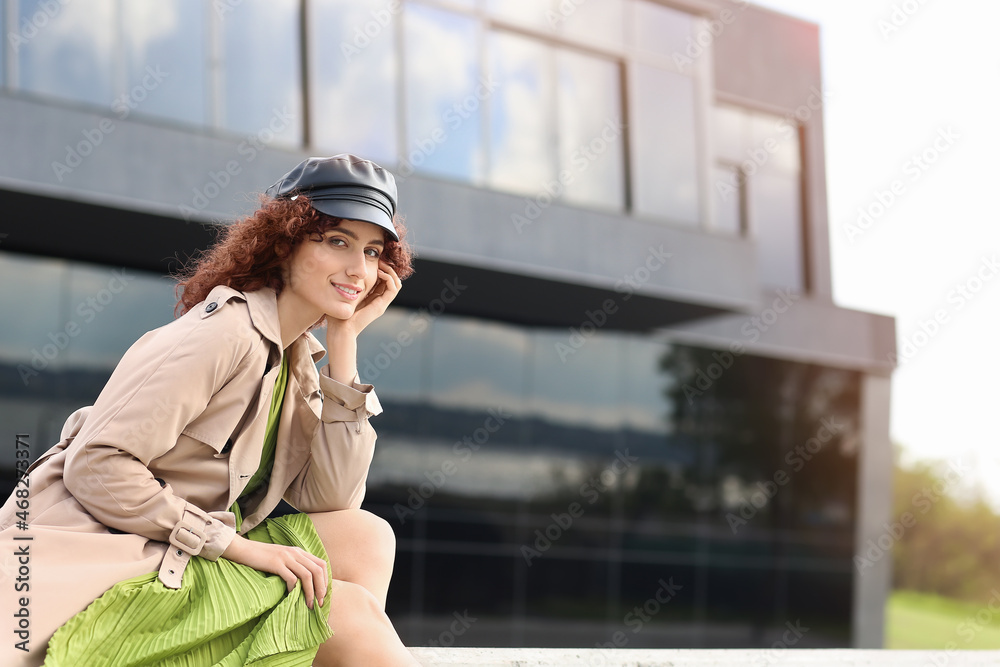 户外现代建筑附近戴着皮帽的快乐年轻女子