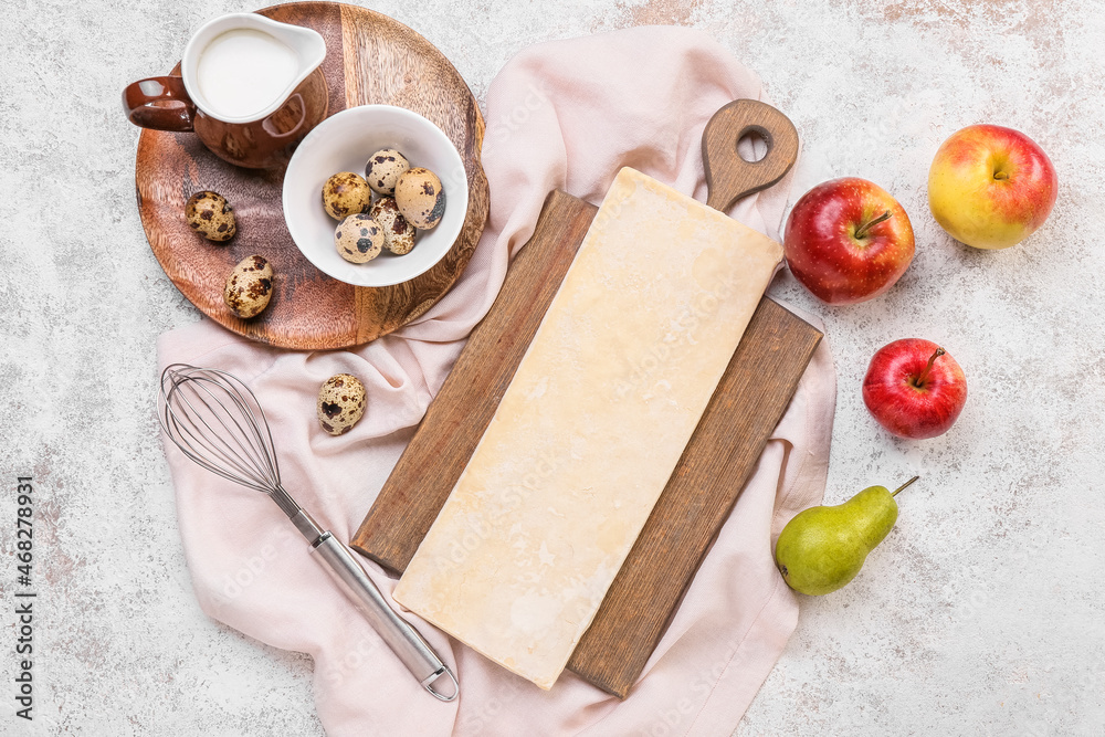 Board with fresh dough and ingredients for apple strudel on light background