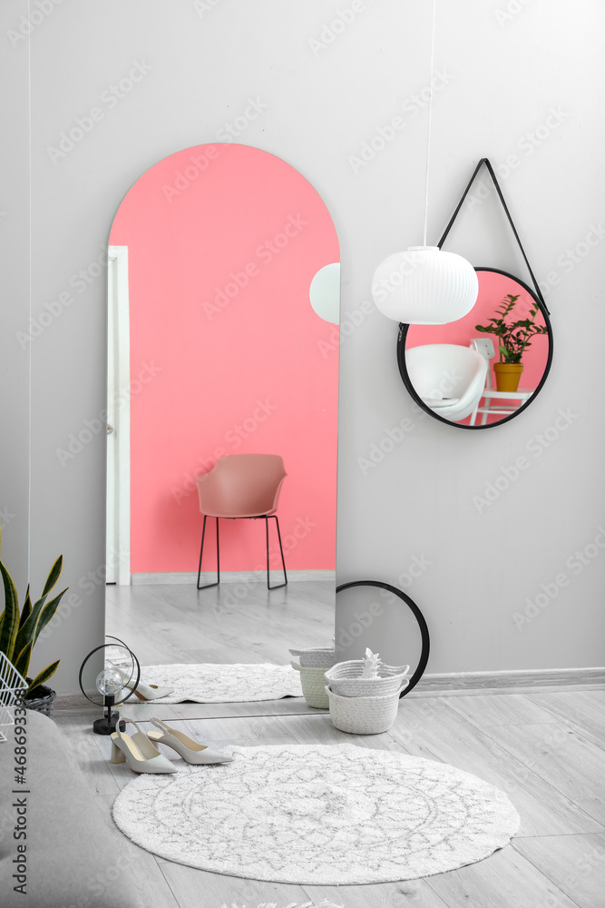 大镜子，粉色扶手椅和浅色走廊的墙壁反射