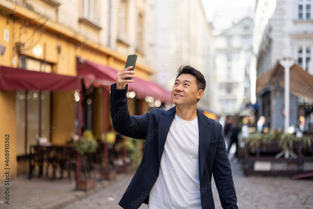 亚洲商人在老城散步时用智能手机录制视频。概念视频博客和b