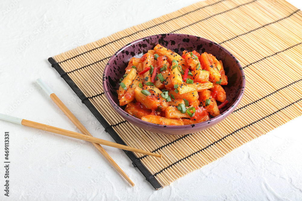 Plate with honey chilli potato and chopsticks on light background