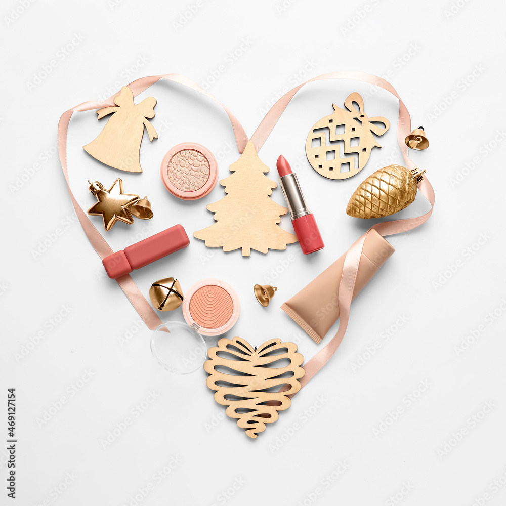 Heart made of makeup cosmetics and Christmas decor on white background