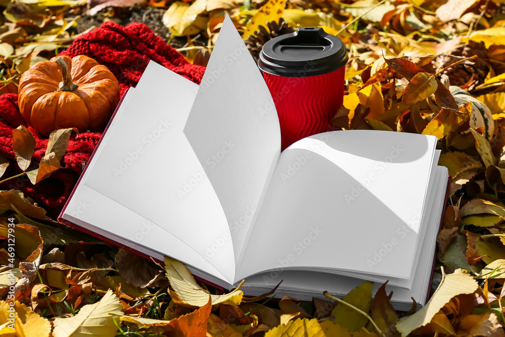 秋季公园里打开的书，有空白页、围巾和纸杯咖啡