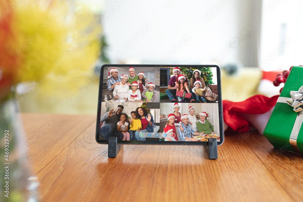 Happy diverse families smiling on tablet group video call screen at christmas time