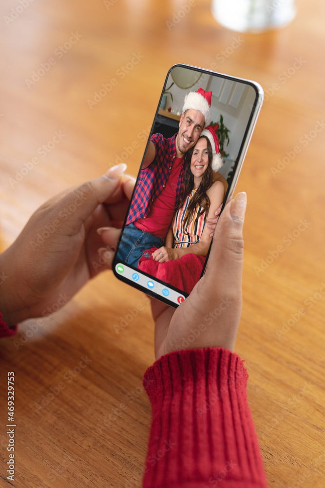 戴着圣诞老人帽微笑的高加索夫妇用智能手机进行圣诞视频通话的女人的手