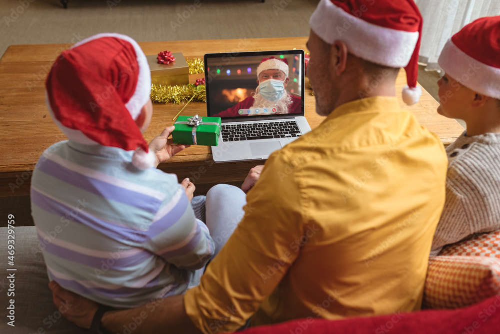 高加索父子与戴口罩的圣诞老人进行笔记本电脑圣诞视频通话