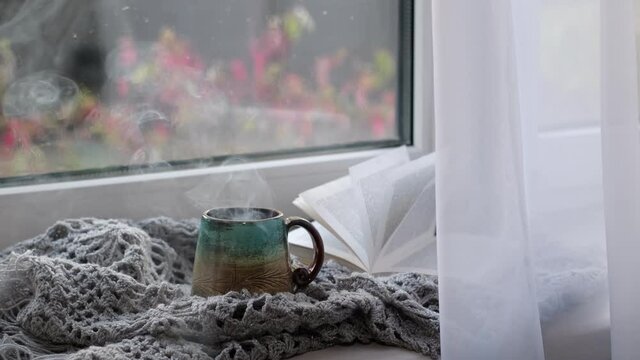 Close up video. Steaming coffee cup on a rainy day window background. cozy atmosphere, in cold weather. Rainy Day Mood.