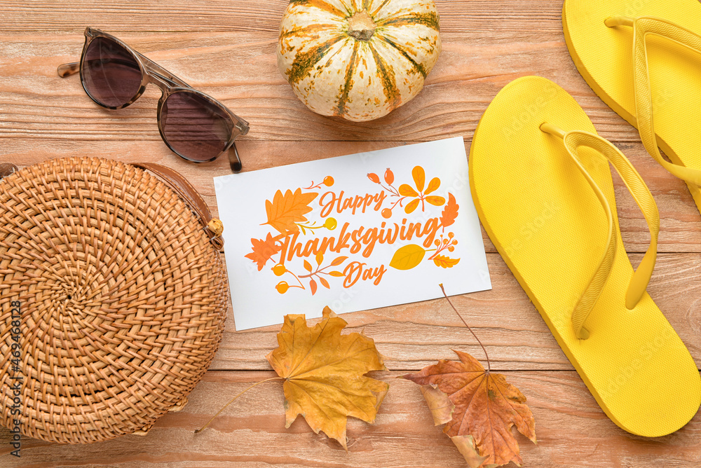 Stylish bag, sunglasses, pumpkin, flip flops, dry leaves and paper card with text HAPPY THANKSGIVING