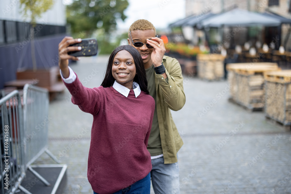 年轻的黑人夫妇在户外用智能手机自拍。英俊的微笑男女。概念