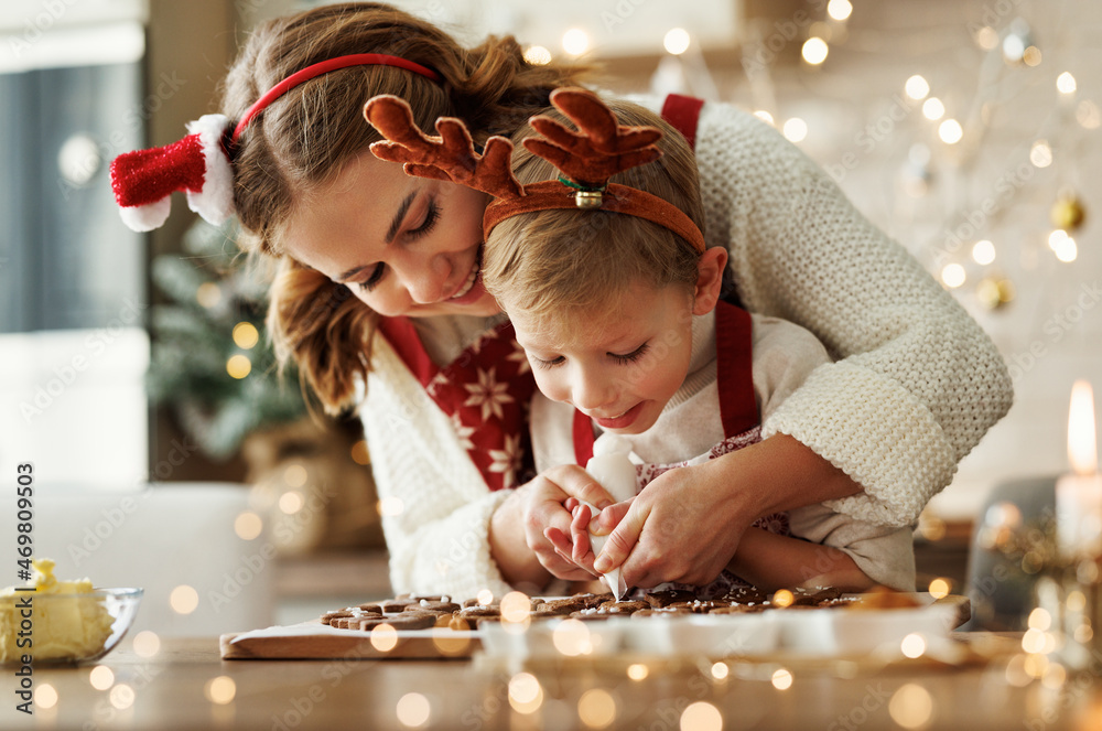 幸福的家庭母亲和儿子穿着围裙在家一起做圣诞饼干