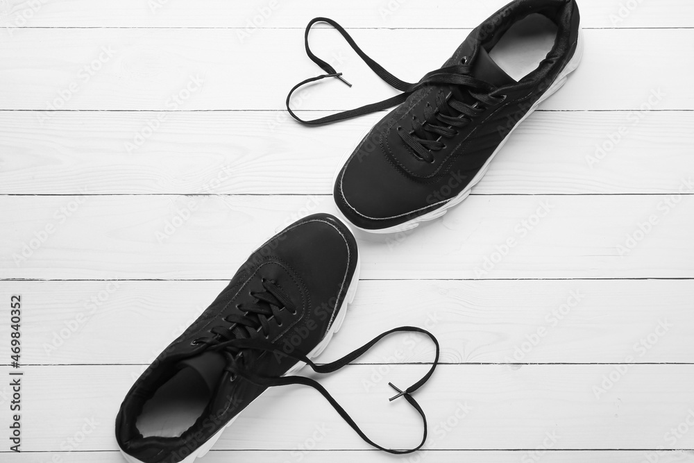 一双运动鞋和浅色木质背景上由鞋带制成的心形
