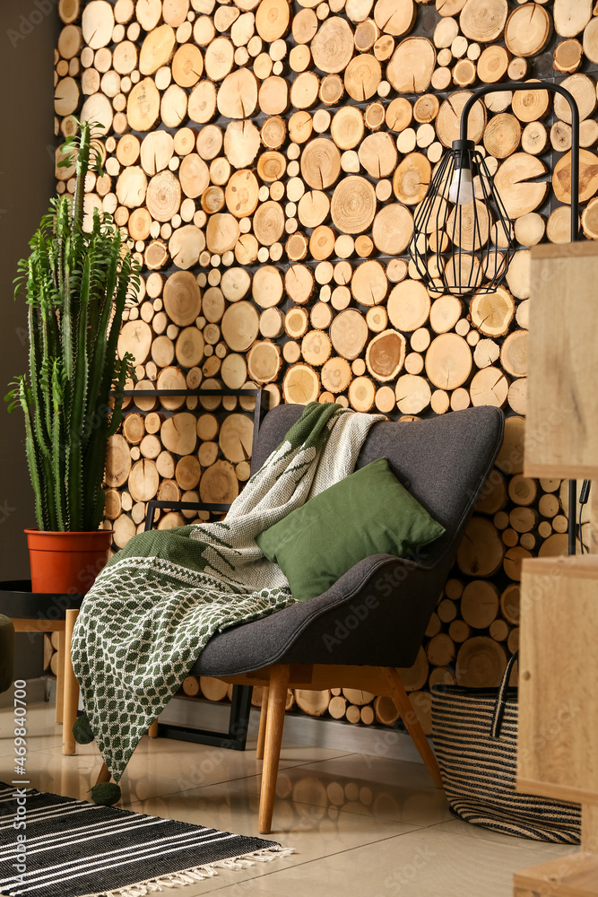 木墙上有枕头、格子和绿色仙人掌的扶手椅