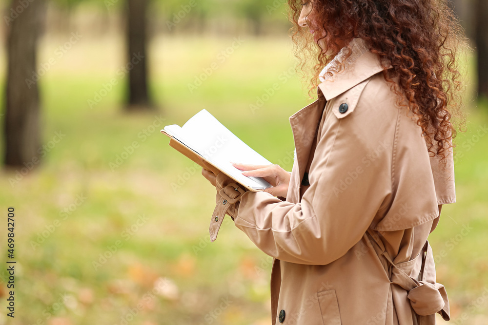 年轻的非裔美国女性在秋季公园看书