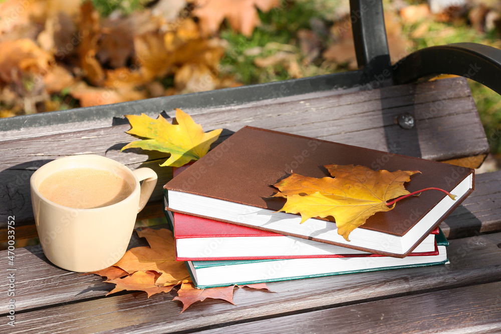 秋天公园长椅上的一叠书和一杯咖啡