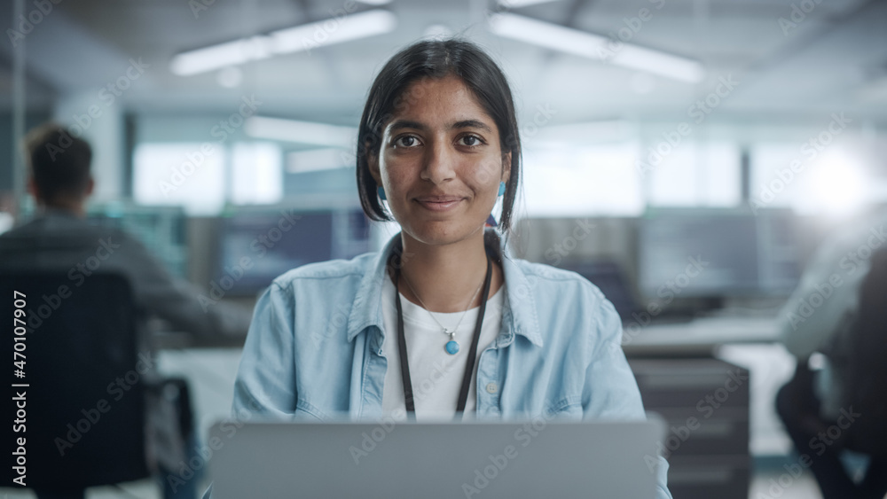 多样化的办公室：美丽的印度IT程序员在台式机上工作的肖像，微笑和