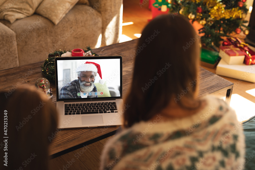 母女俩与戴圣诞老人帽的非洲裔老人进行笔记本电脑圣诞视频通话