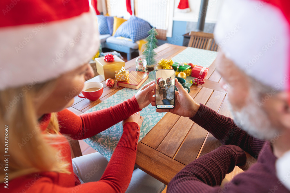 戴着圣诞老人帽的白人夫妇与不同的资深朋友进行智能手机圣诞视频通话