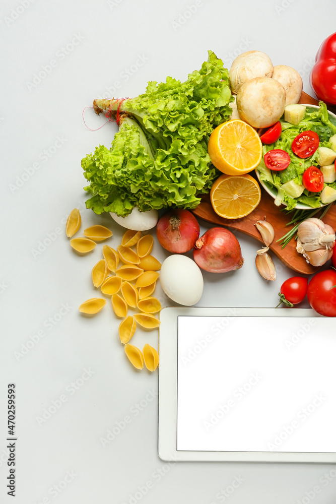 Tablet computer with blank screen and healthy products on light background