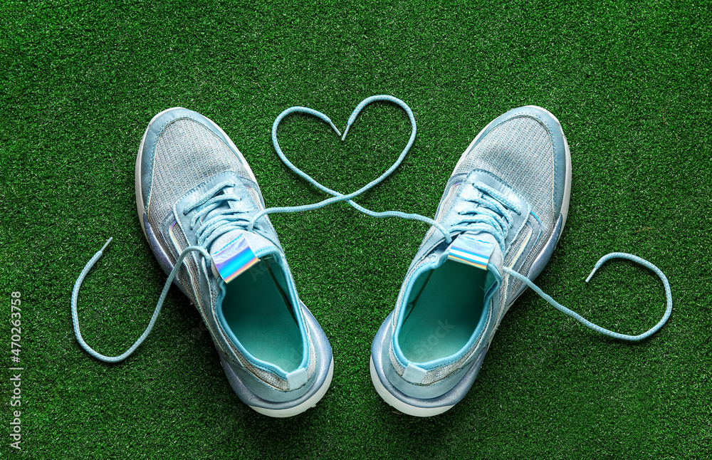 Pair of shoes and heart made of laces on color background