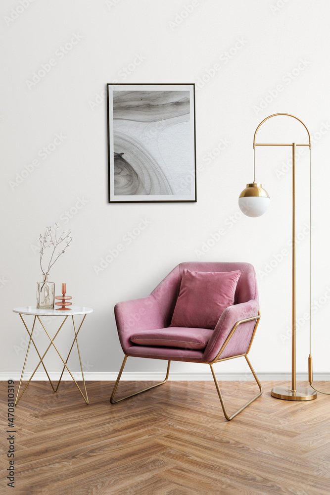 粉色天鹅绒扶手椅旁的抽象艺术画框