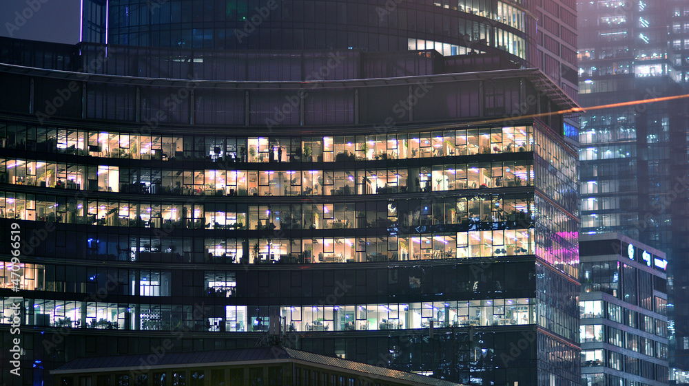 夜间企业建筑-商业理念。玻璃墙办公楼。现代办公窗户